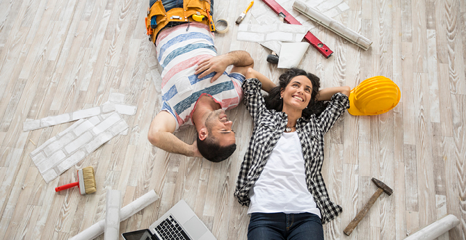 man and woman laying on ground surrounded by construction items.